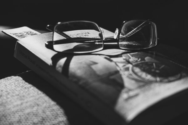 Reading glasses sitting on a copy of Proust's The Way by Swann's